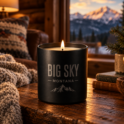 Lit Big Sky Shadow candle on a lodge side table with a Montana mountain view